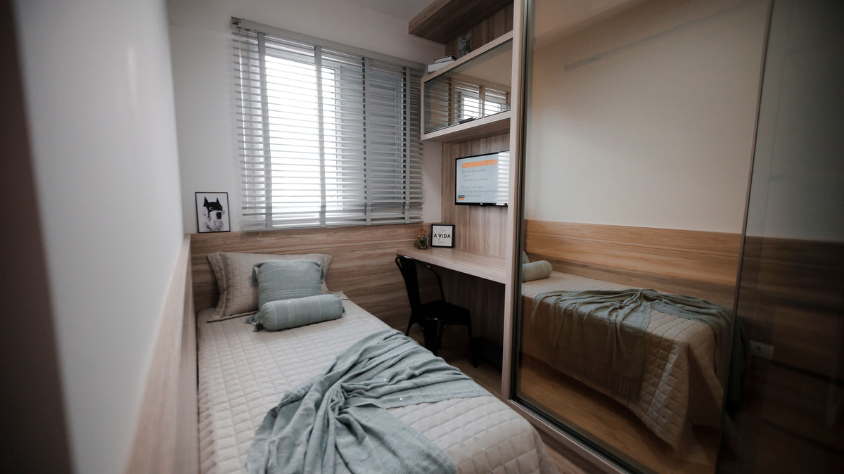 A small tidy bedroom with a single bed against the wall and a compact desk beside it